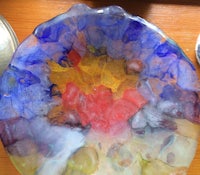 a colorful plate on a table next to a pair of glasses